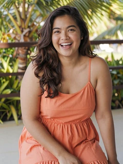 Filipino woman in coral sundress laughing on tropical terrace for dating profile